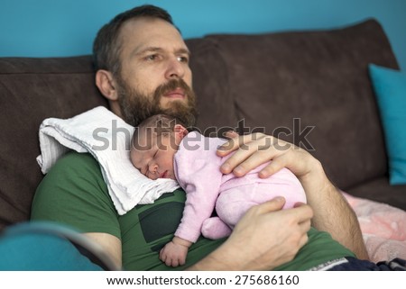14-day baby sleeping on the stomach of his father with a beard