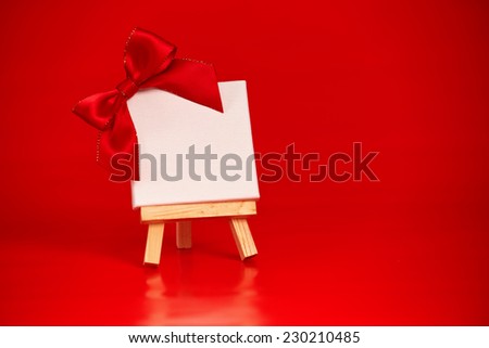 wooden easel with blank canvas on christmas red background