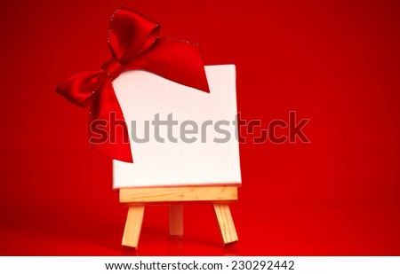 wooden easel with blank canvas on christmas red background