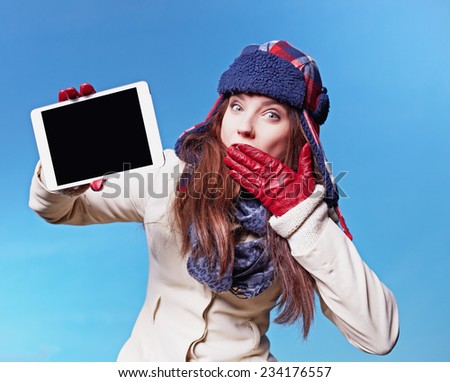 christmas, x-mas, electronics, gadget concept - smiling woman in winter clothes with tablet pc on blue background