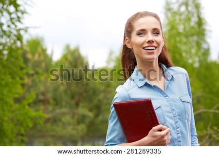 Pretty young woman student in the park. Beauty smiling girl outside.