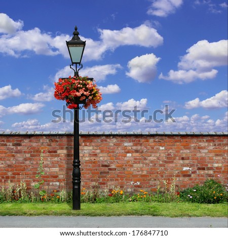 A Red Brick Wall with an Old Street Light and Blue Sky