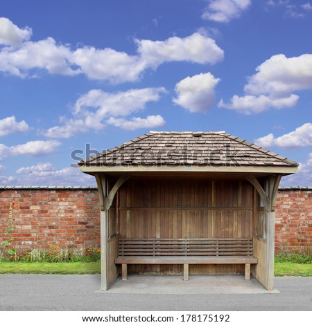 An Old Wooden Bus Shelter with Red Brick Wall and Blue Sky