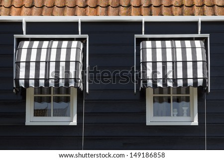 Architectural detail of a typically Dutch wooden house\'s windows with awnings.