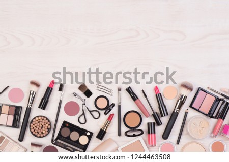 Makeup cosmetics such as eyeshadows, lipstick, mascara and makeup accessories on white, wooden background, top view with copy space