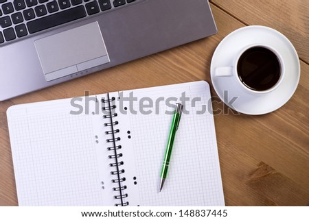 Open notebook on desk with coffee and laptop