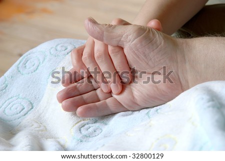 Young person holding an old man\'s hand.