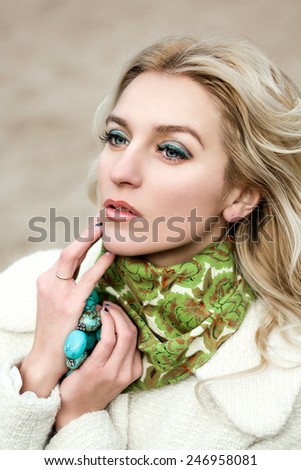 Fashion portrait of blonde long hair woman with green scarf and jewelry outdoor