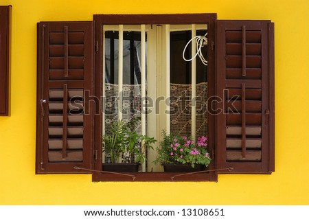 brown shuttered window on yellow wall