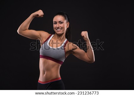 Young sports-looking nice lady with dark hair on the black background in studio
