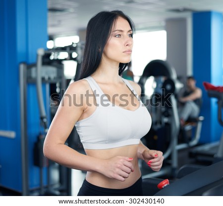 young sexy lady running on treadmill in gym