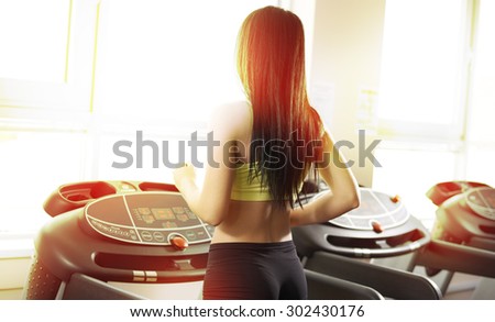 young sexy lady running on treadmill in gym
