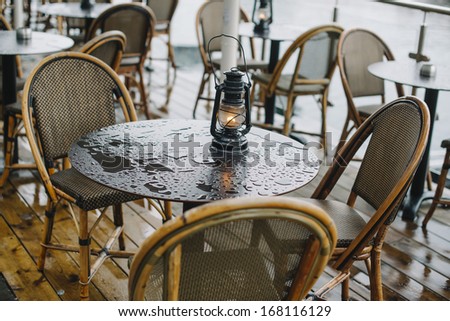 Wet cafe table after rain with a lantern on it