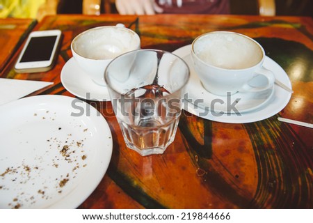 empty cups of coffee at the coffee table and a smartphone on the background