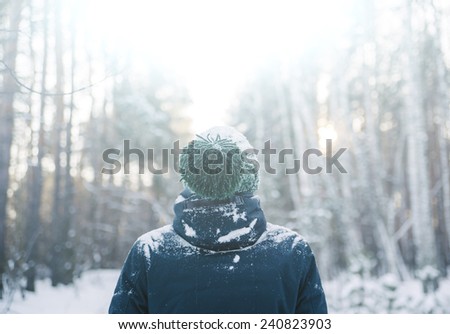 young man in a winter outfit standing in the middle of a winter snowy forest