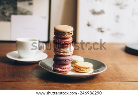 Fresh morning espresso coffee with some delicious french macarons dessert on a plate on an old  wooden table background
