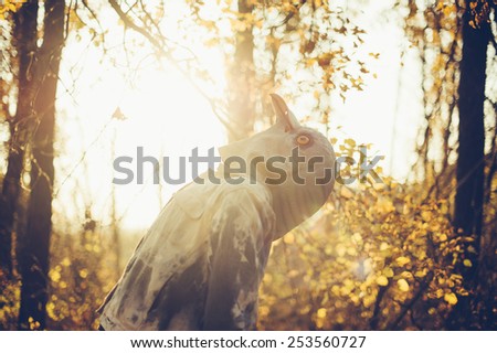 Weird man in a creepy rubber pigeon bird mask in the autumn sunset forest