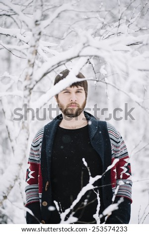 funny geeky hipster man making funny faces in the snowy winter forest