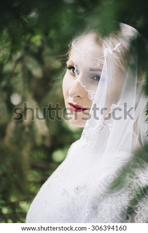 Beautiful bride in a white dress and a veil forest portrait