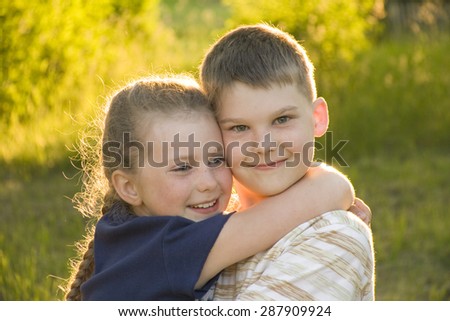 brother and sister hugging on sunny meadow