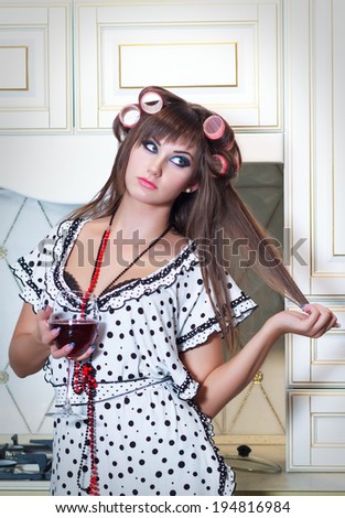Housewife with her hair in curlers and a glass of wine in the kitchen.