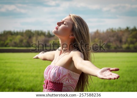 Beautiful young woman enjoying unity with nature; spring or summer time concept