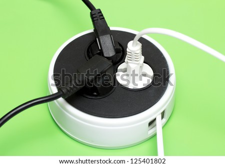 Electrical plugs and outlet on a green background