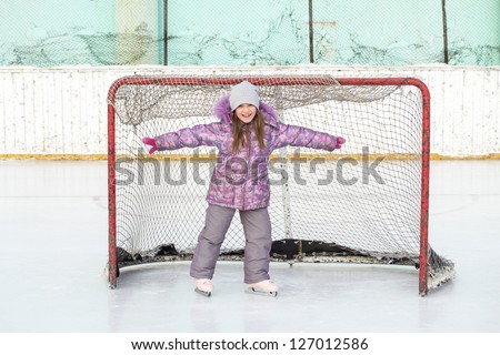 little girl on the hockey ice field in the gate