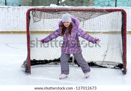 little girl on the hockey ice field in the gate
