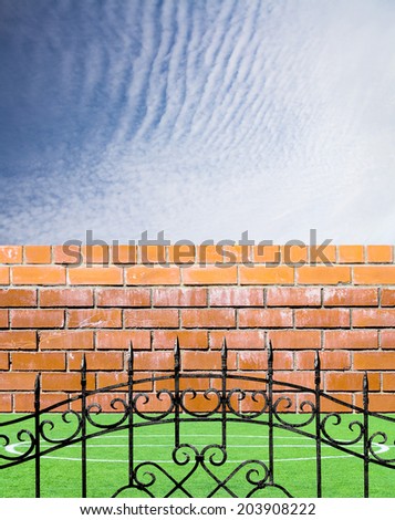 Old brick wall, metal fence and green grass on a sky background