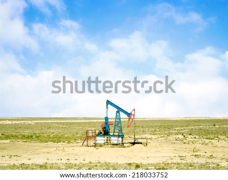pumping oil from an oil well on the background of sky with clouds