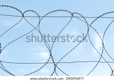 Barbed metal wire against the blue sky