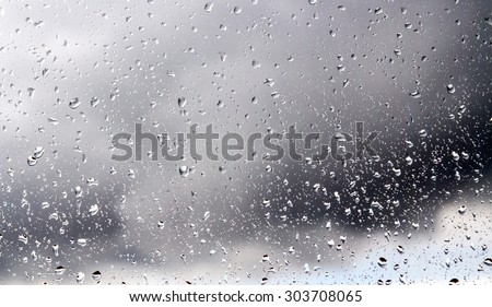 Raindrops on a window pane on the background of a stormy sky.