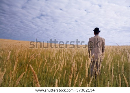 man in hat and suit stand in field with golden grass