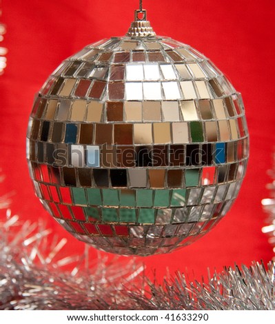 Christmas mirror ball on red background with garland