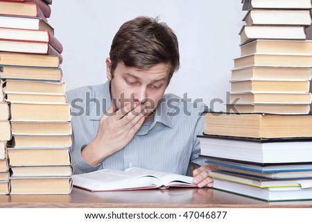 Young surprised student reading book between books