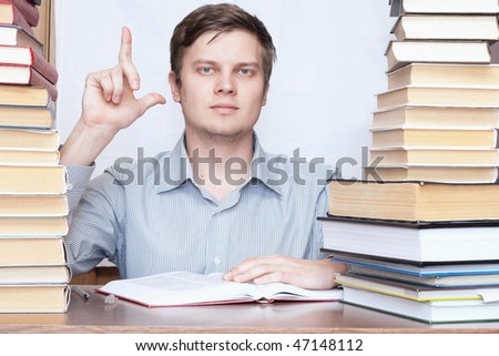 Young serious man show finger to up between books
