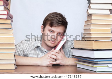 Young serious student sitting between books and think