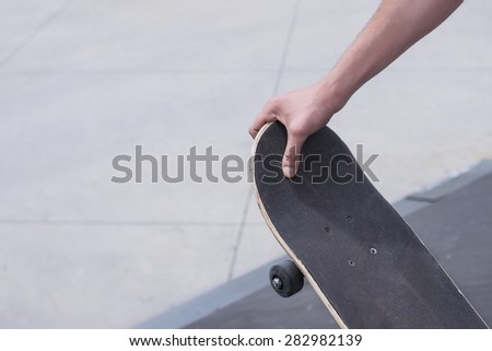 Close up of skateboarder holding skate board at skate park