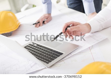 Business people on meeting in bright modern office with blueprint at desk check documents and business workflow on laptop