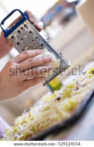 Close up of woman preparing a pizza, hand placing ingredients on pizza.