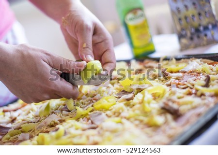Baker\'s hand placing ingredients on pizza