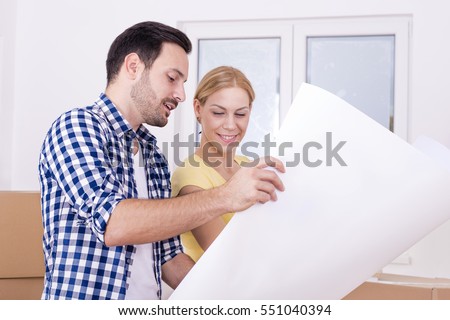 Young couple discussing plan of their new house. Moving and real estate concept
