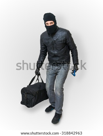 Masked burglar or thief with balaclava is sneaking with black bag.