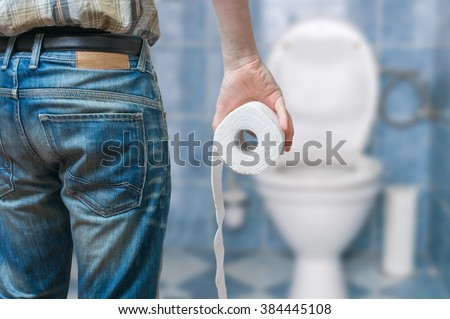 Man suffers from diarrhea holds toilet paper roll in front of toilet bowl.