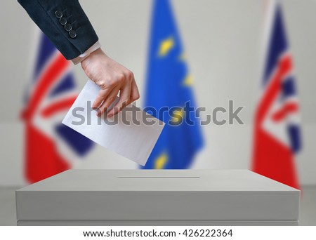 Election or referendum in Great Britain. Voter holds envelope in hand above vote ballot. British and European Union flags in background.