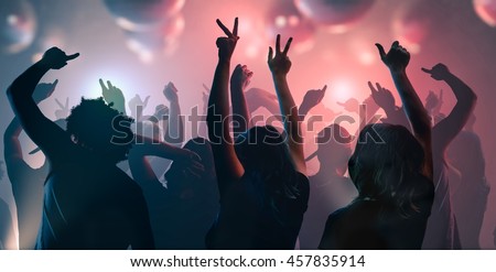 Nightlife and disco concept. Young people are dancing in club.