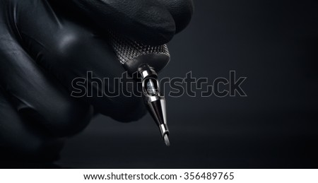 Tattoo artist holding tattoo machine on dark background closeup,Machine for a tattoo concept