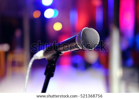 Close up of microphone in concert hall or conference room on colorful blurred background