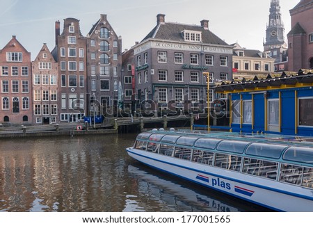 AMSTERDAM, NETHERLANDS - 27 FEB. 2013: Canal boat is tied up along one of the larger canals in the centre of Amsterdam at  Damrak. The canals and their boat trips are a major tourist attraction